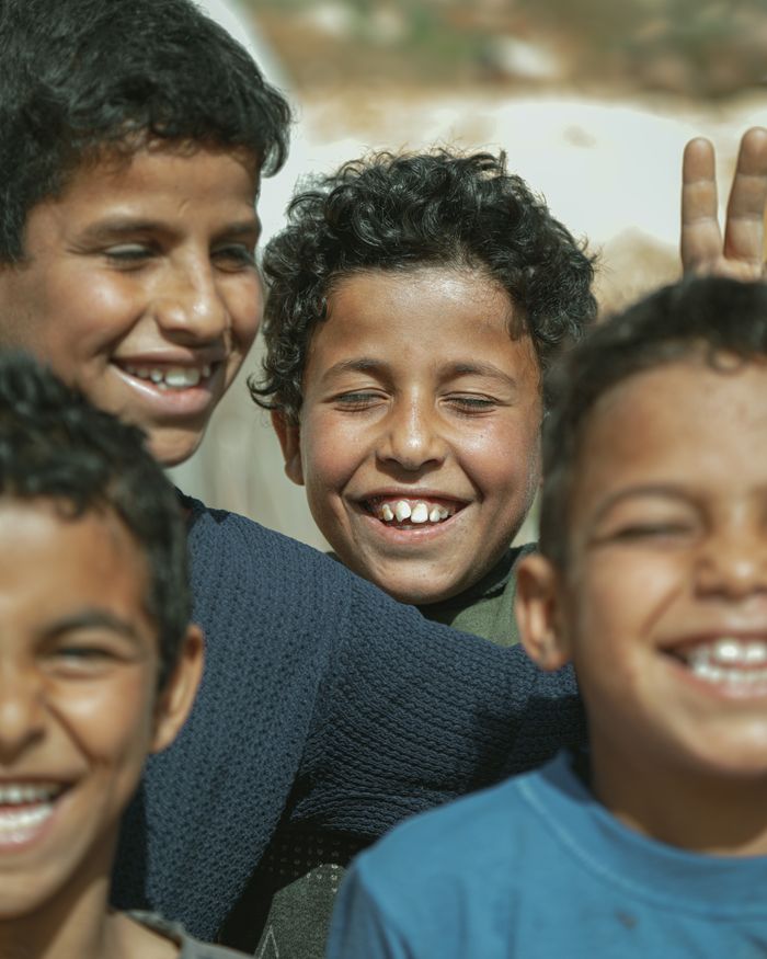A group of boys happily smiling and enjoying a sunny day outdoors in Syria.