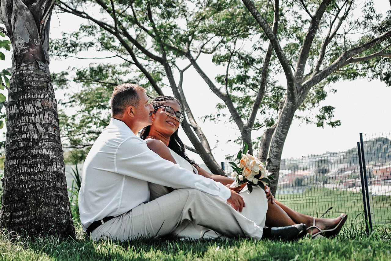 A couple sharing a loving moment under a tree in a serene park setting.